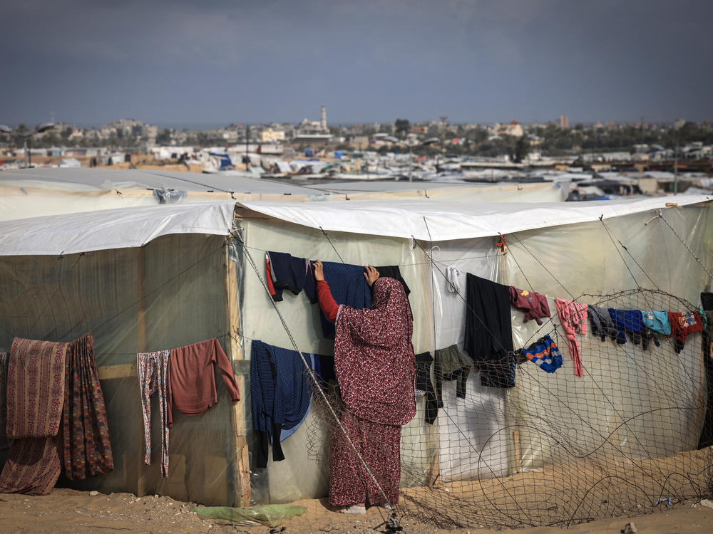 A displaced Palestinian woman hangs laundry to dry outside a tent at a makeshift camp on the Egyptian border, west of Rafah in the southern Gaza Strip on Jan. 14.