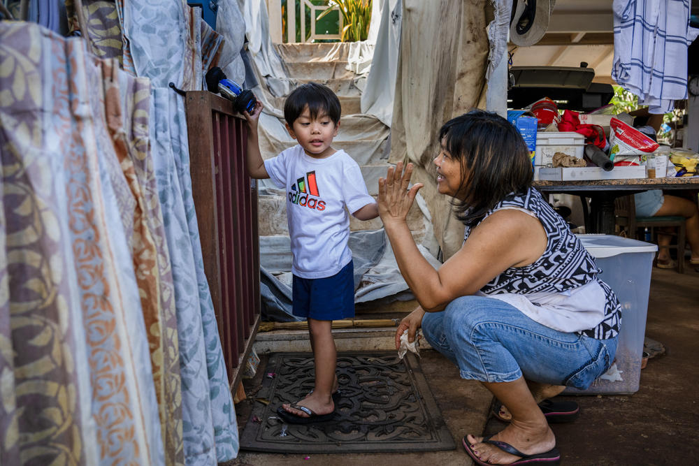 Emelyn Andres plays with her grandson Sebastian. She came to clean and pull ash-soiled contents out of her house, and haul it to the landfill. 