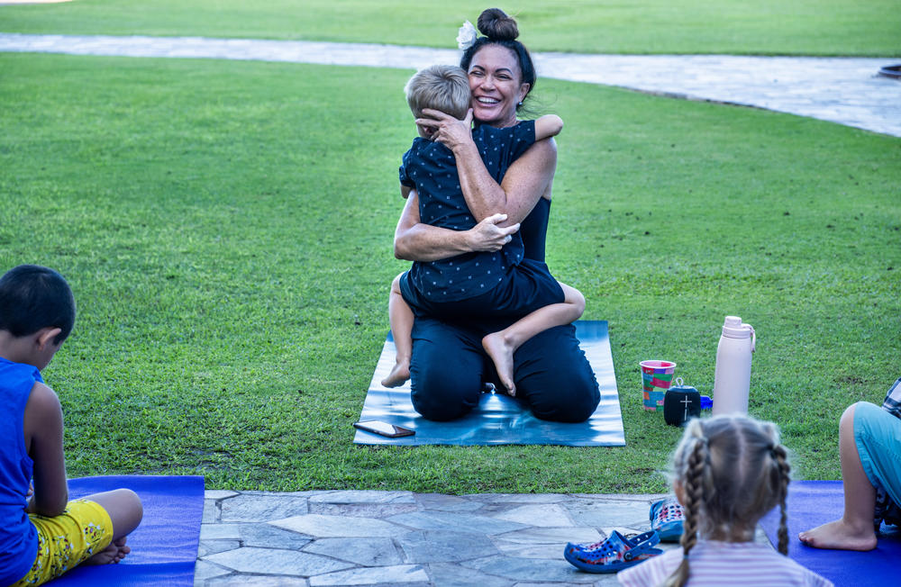 Kilihune Ka'aihue gets a hug from a child after she teaches a yoga class to displaced children from Lahaina, many who lost their homes.