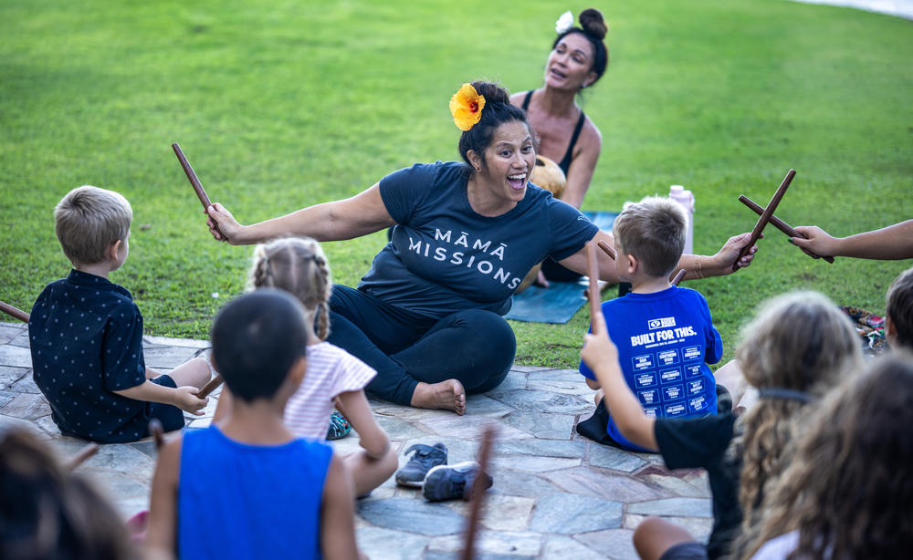 Leialoha Lani-Montira teaches a hula and music class. Yoga teacher, Kilihune Ka'aihue is behind her playing an ipu.
