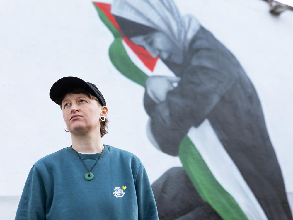 Emmalene Blake poses for a portrait in front of her mural showing Samia al-Atrash holding her niece Masa Khader, who was killed by an Israeli airstrike in Gaza in October.