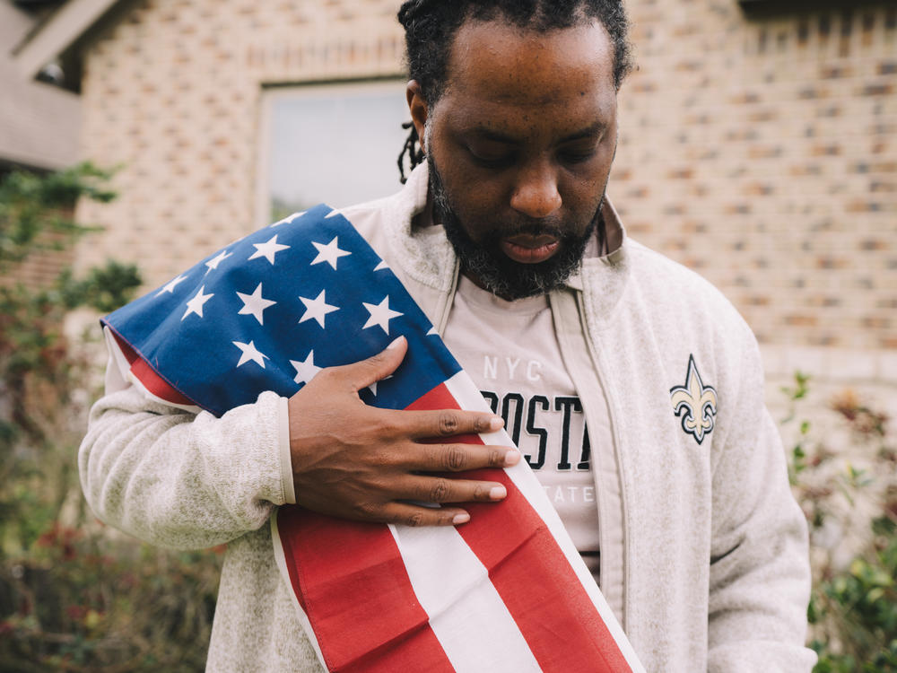 Edmund Garcia, an Iraq war veteran, holds the American flag over his shoulder outside his home on Thursday in Rosharon, Texas.
