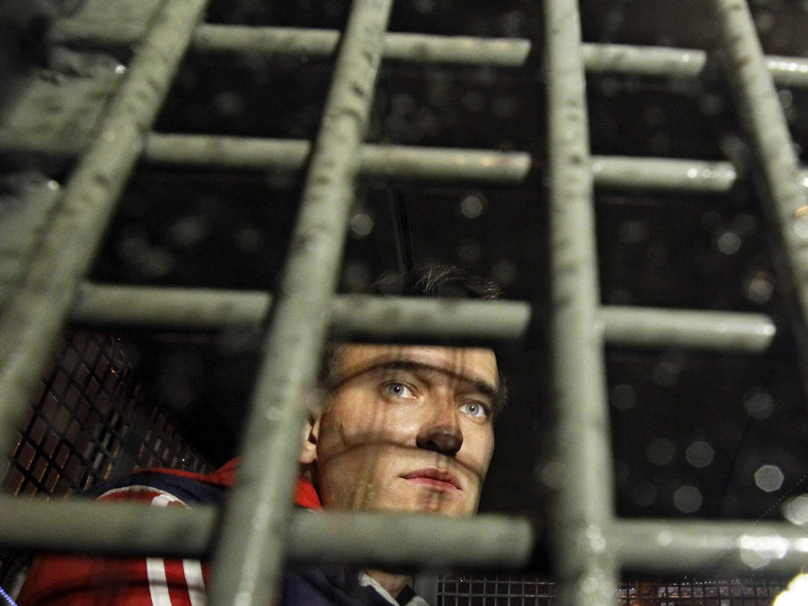 Alexei Navalny is seen in 2012 behind the bars in a police van after he was detained during protests in Moscow a day after Vladimir Putin's inauguration.