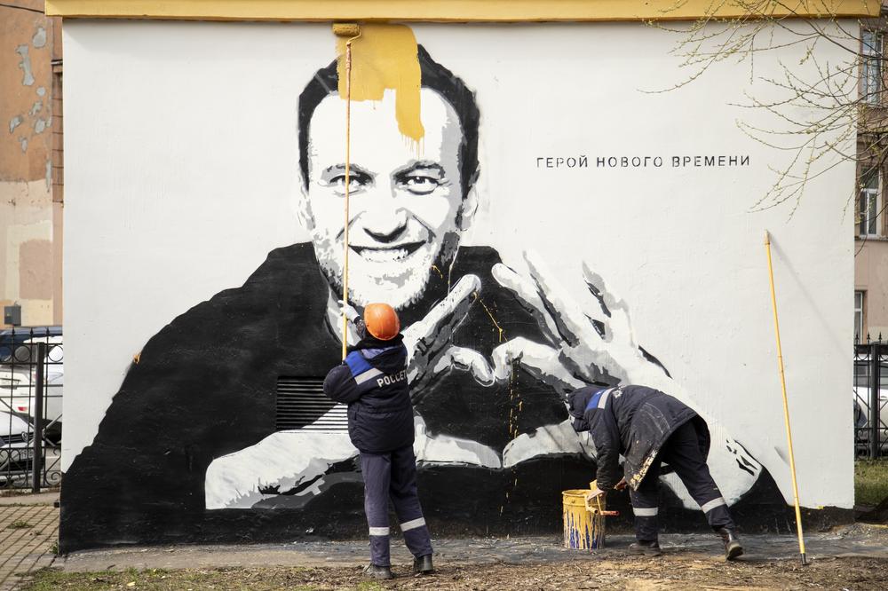 April 28, 2021: Municipal workers paint over graffiti of Russia's imprisoned opposition leader Alexei Navalny in St. Petersburg, Russia . The worlds on the wall reading 
