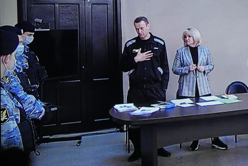 March 22, 2022: Russian opposition leader Alexei Navalny, centre, gestures via a video link provided by the Russian Federal Penitentiary Service, standing next to his lawyer and speaking with Penitentiary Service officers during a court session, in Pokrov.