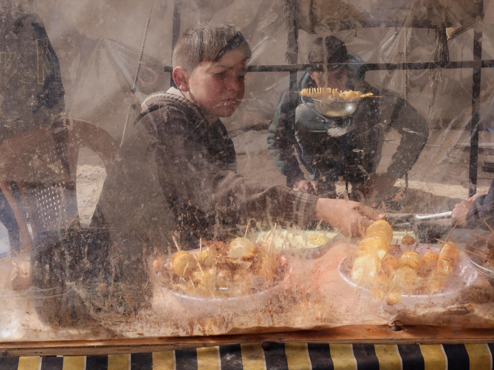 A displaced Palestinian boy sells homemade potato chips outside a tent camp in Rafah on Tuesday, Feb. 13.