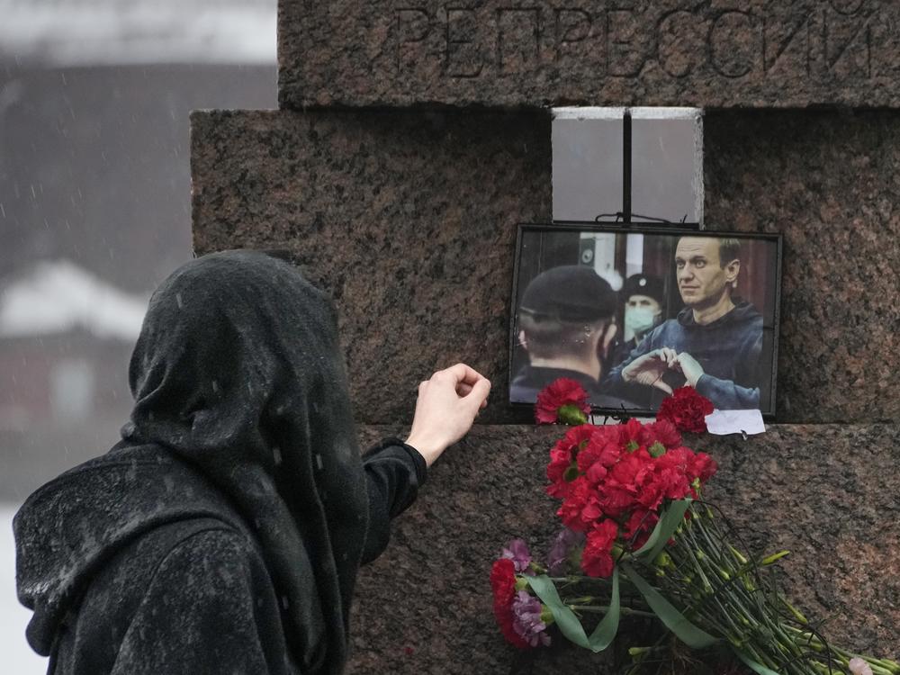 A woman touches a photo of Alexei Navalny after laying flowers at the Memorial to Victims of Political Repression in St. Petersburg, Russia, on Saturday.