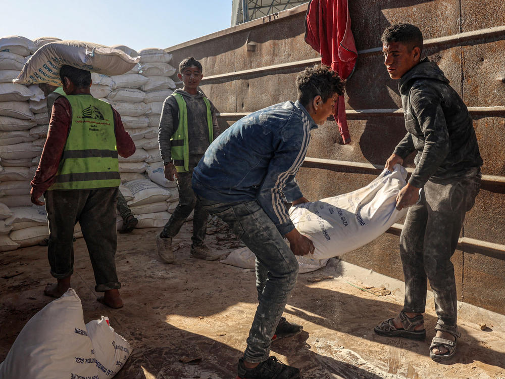 Workers unload bags of humanitarian aid that entered Gaza by truck through the Kerem Shalom/Karm Abu Salem border crossing in the southern part of the Palestinian territory on Saturday, Feb. 17.