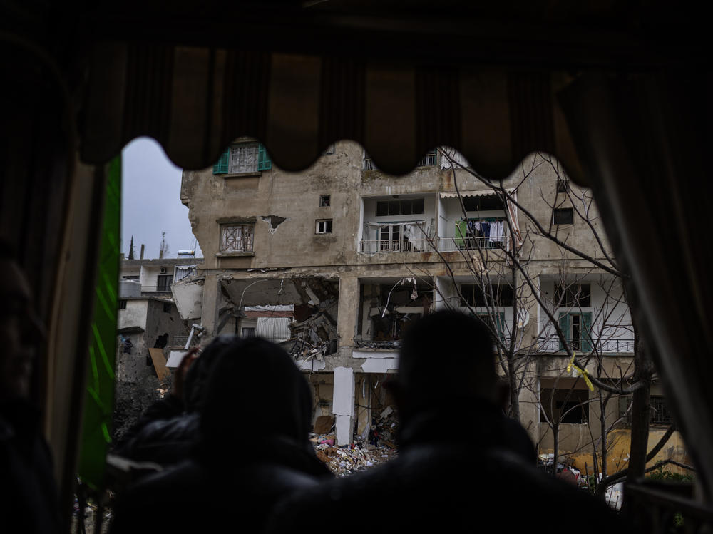 Neighbors and media teams stand in front of a building on Thursday, Feb. 15, that lays in ruins following an Israeli attack that claimed the lives of at least seven members of the same family.