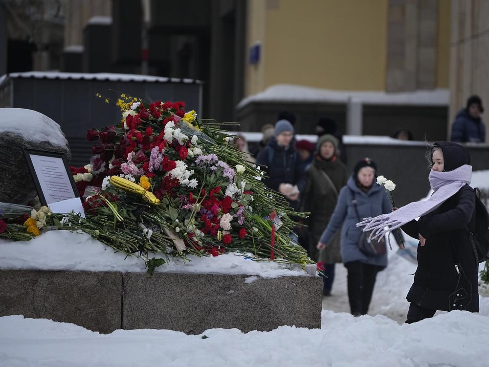 People lay flowers paying the last respect to Alexei Navalny at the monument, a large boulder from the Solovetsky islands, where the first camp of the Gulag political prison system was established, near the historical the Federal Security Service (FSB, Soviet KGB successor) building in the background, in Moscow, Russia, on Saturday morning, Feb. 17, 2024.