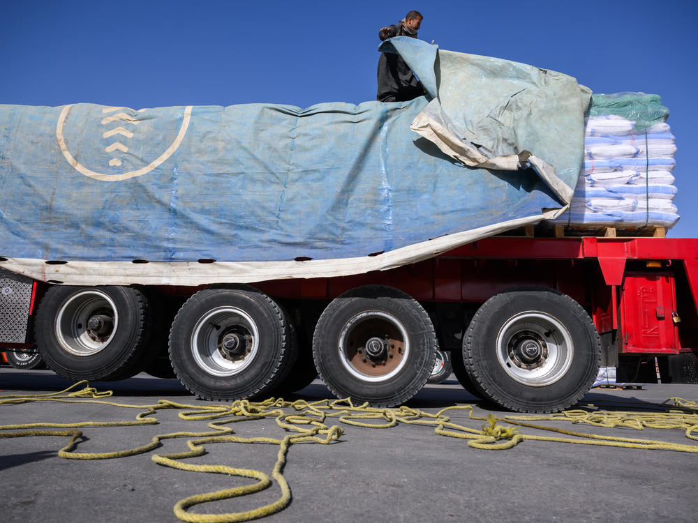 An Egyptian truck driver removes a tarp covering humanitarian aid before it is inspected on its way to the Gaza Strip at the Kerem Shalom Crossing in Israel on Dec. 22, 2023.