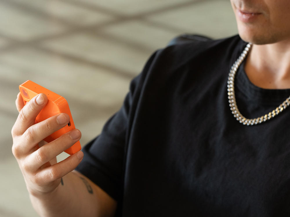 A Rabbit employee demonstrates the company's Rabbit R1 device. The company says more than 80,000 people have preordered the device for $199.