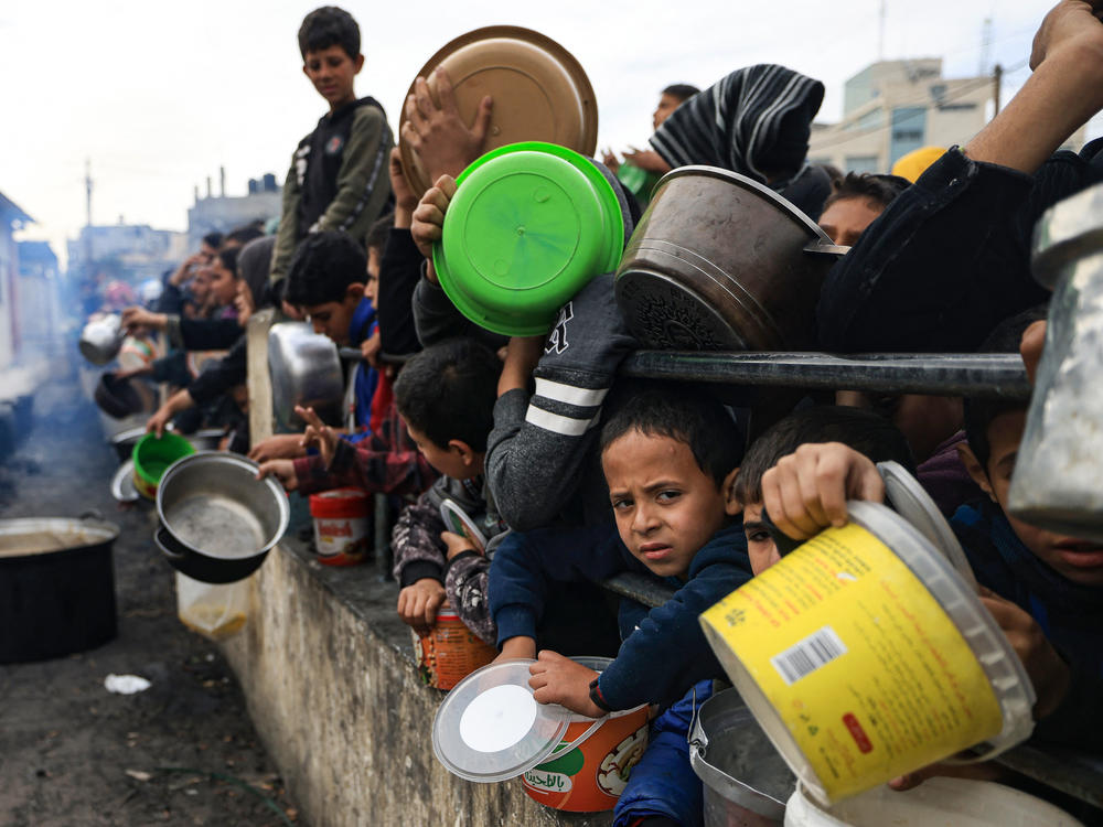 Palestinian children wait to collect food at a donation point in a refugee camp in Rafah in the southern Gaza Strip on December 23, 2023.