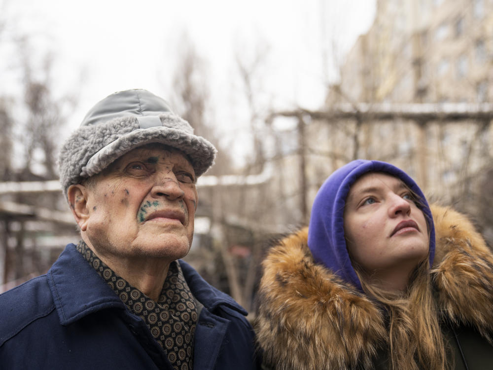 Petro Shevchenko (left) stands with his grandaughter, Olena Parkhomenko, as they survey the damage to their apartment building in Dnipro, Ukraine, on Jan. 16, 2023. Shecchenko, who lived alone on the seventh floor, suffered cuts to his face in the attack.