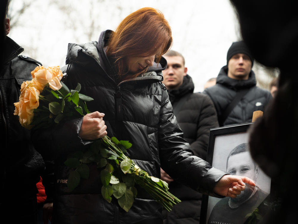 Mykhailo Korenovsky's wife, Olha Korenovska, touches a portrait of her husband at his funeral in Dnipro, in eastern Ukraine, on Jan. 17, 2023. He was a beloved boxing coach and among the more than 40 people who were killed in a Russian strike.