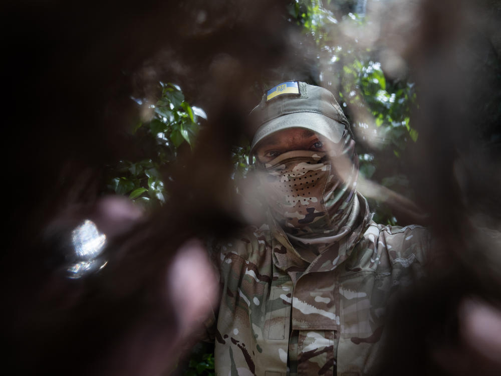 Ukrainian soldier Michel looks through camouflage netting near his home in Kherson, in southern Ukraine, in March.