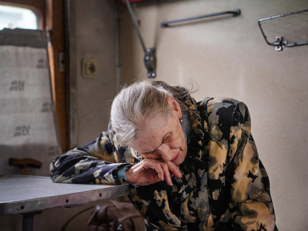 Lyudmilla Nesterova leans on a table in the evacuation train after a group of rescue workers helped her and her husband leave Toretsk.