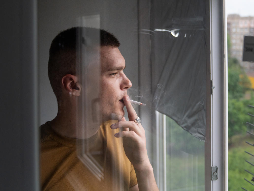 Rescue worker Eduard Skoryk smokes a cigarette while looking out the window of his apartment in Kramatorsk, in eastern Ukraine, in May.