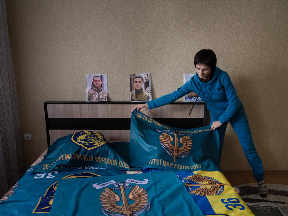 Nataliya Kucherenko drapes a flag over the bed in her son's room in the Sumy region of Ukraine. He was captured by Russian forces in Mariupol and Kucherenko waits for him to be returned.