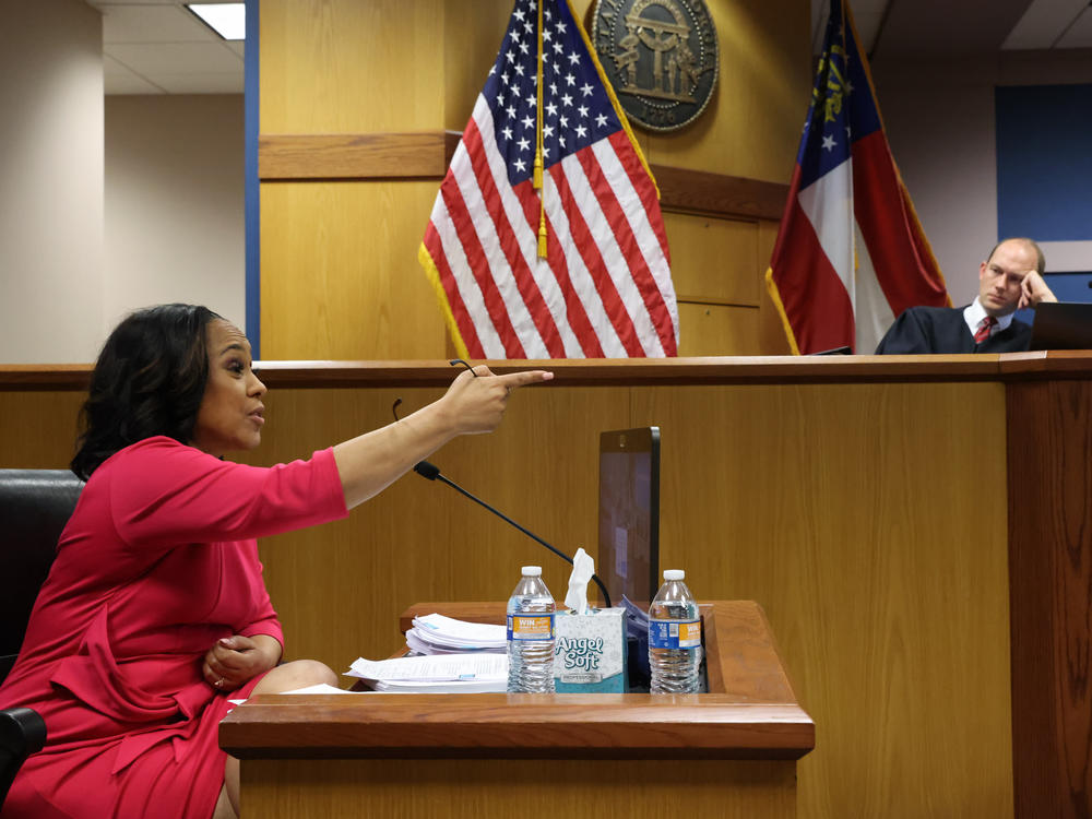 Fulton County District Attorney Fani Willis speaks from a witness stand in front of Fulton Superior Judge Scott McAfee during a Feb. 15 hearing about whether Willis' office should be disqualified from the Georgia election interference case.