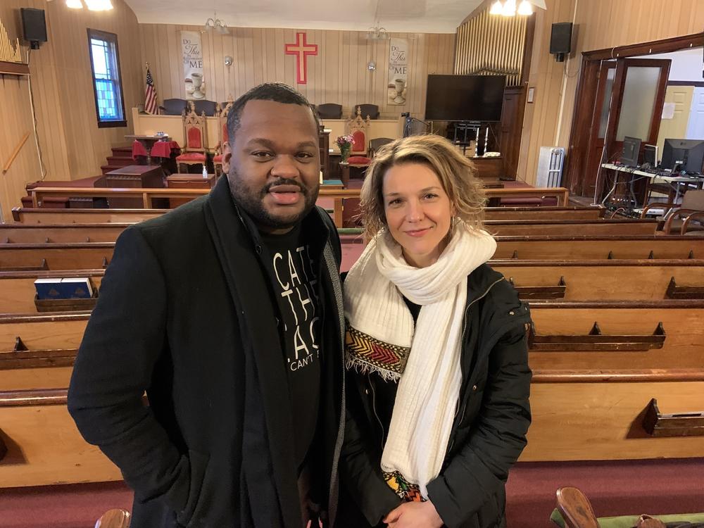 Rev. Terrance A. King, pastor, and Paula Ioanide, member, stand in the sanctuary of St. James A.M.E. Zion Church in Ithaca, New York. They worked with BlocPower to convert the gas heating system to more efficient electric heat pumps, that also will cool the building in summer.
