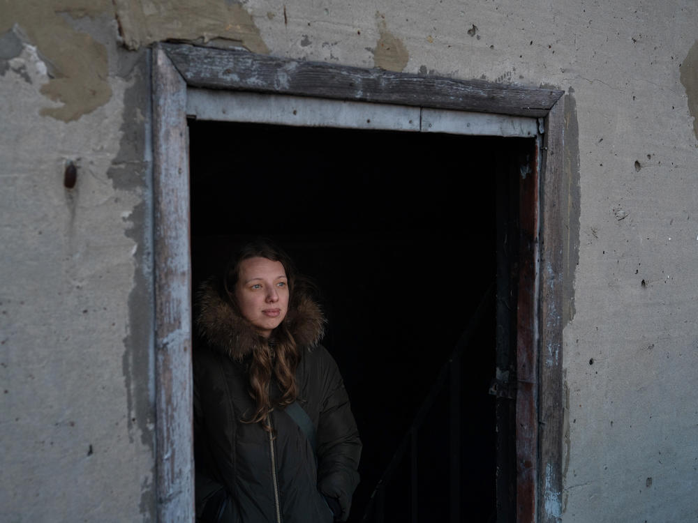 In March 2023, journalist Polina Lytvynova stands in a doorway of a destroyed building in Saltivka, a neighborhood of Kharkiv, Ukraine, that was severely damaged in the early stages of the war in 2022.
