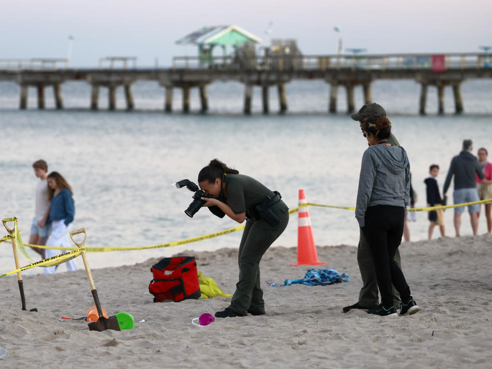 Investigators on the beach in Lauderdale-by-the-Sea, Fla., take photos of the scene of a sand collapse on Tuesday, Feb. 20, 2024.