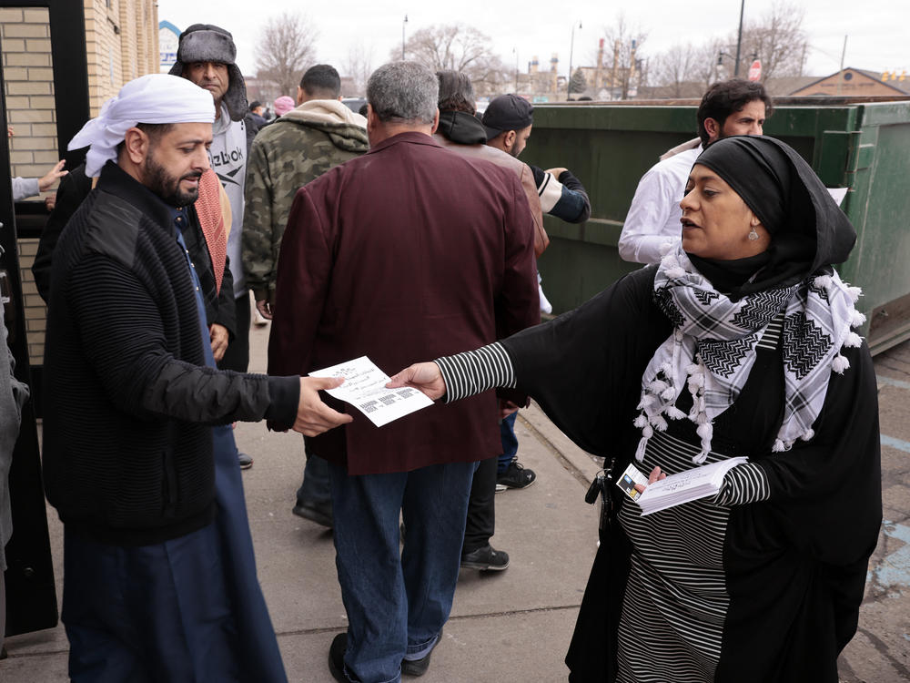 Samraa Luqman (R) hands out fliers outside of the American Moslem Society Mosque to ask voters not to vote for President Biden in Dearborn Heights, Mich., on Feb. 16, 2024.