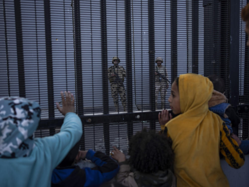 Displaced Palestinians at the southern end of Gaza look through the border fence at Egyptian soldiers on the other side on Jan. 14.