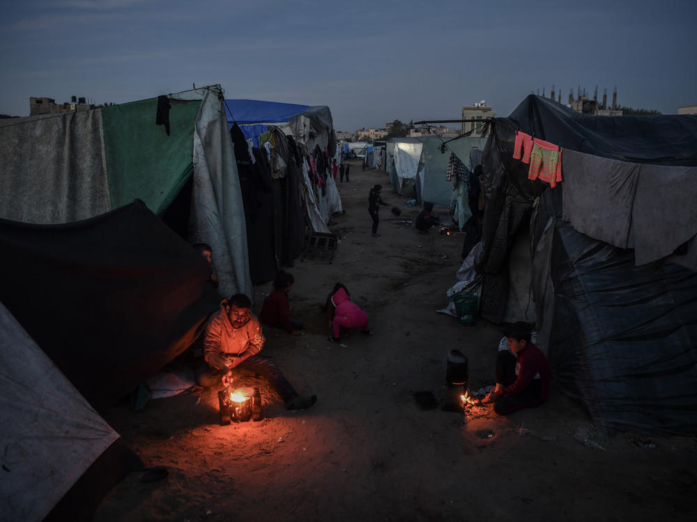 Palestinian families have been repeatedly displaced due to Israel's attacks on the Gaza Strip. Here a family living in a tent sits around a fire in Rafah, in southern Gaza, on Feb. 22.