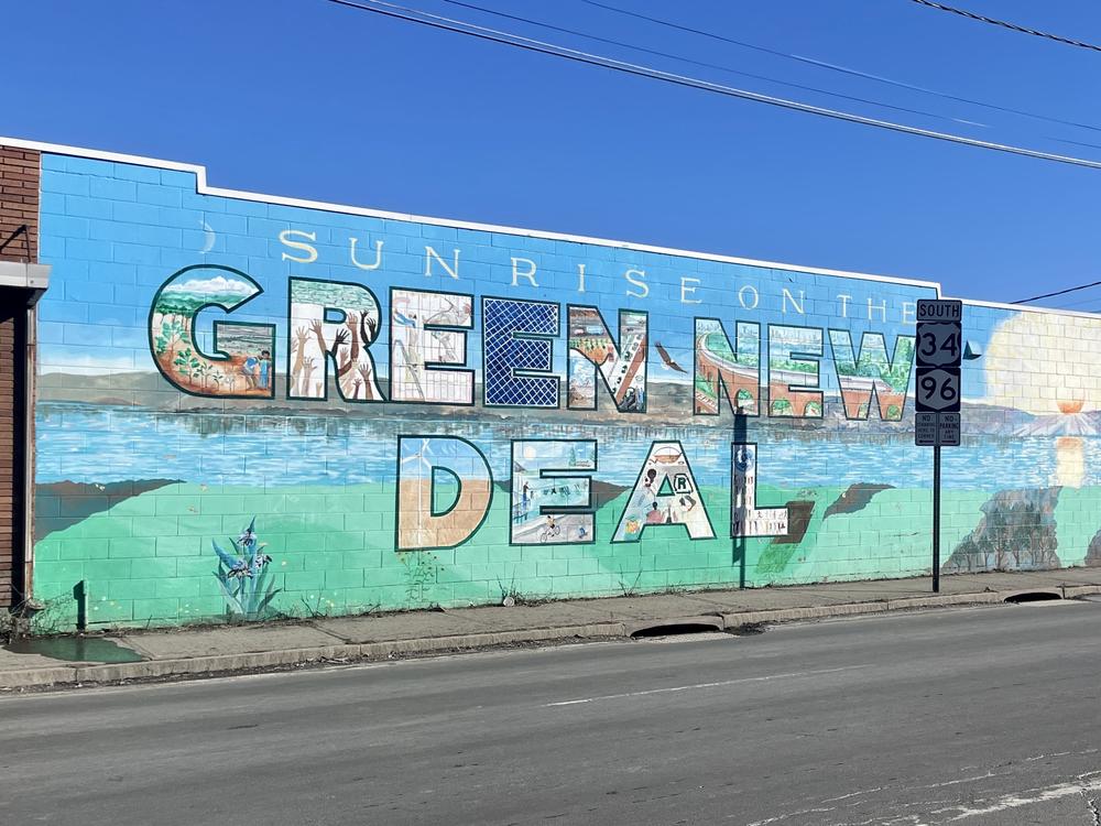 A mural on the edge of downtown Ithaca, New York marks the college town's 2019 passage of a Green New Deal. The city aims to zero out its climate-warming greenhouse gases by 2030.