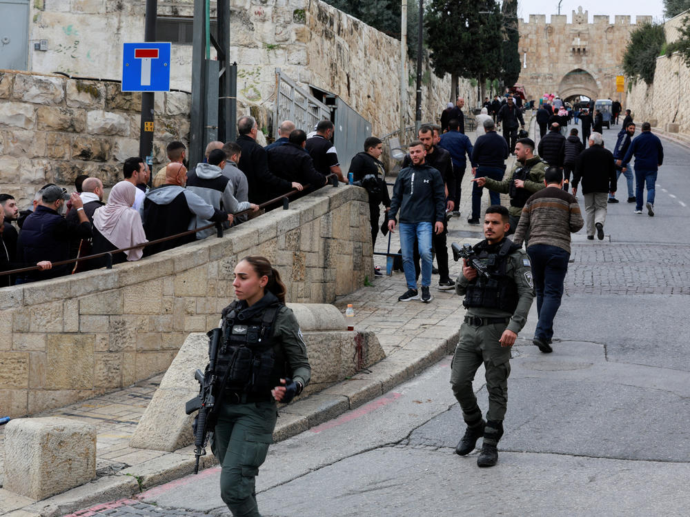 Palestinian attend Friday prayers while Israeli Border Police officers stand guard in Jerusalem on Friday, Feb. 23.