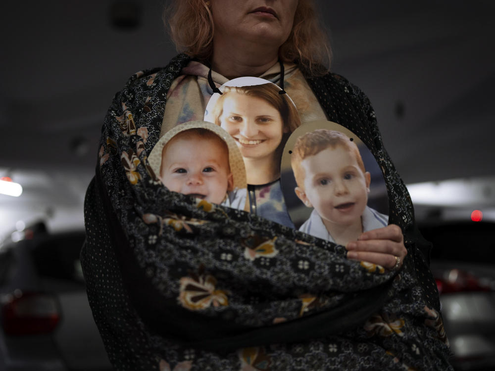 A woman holds a mask depicting the faces of Shiri Bibas and her sons Kfir and Ariel, Israelis who are being held hostage in Gaza, during a protest on Wednesday, Feb. 21, in Tel Aviv to demand their release.