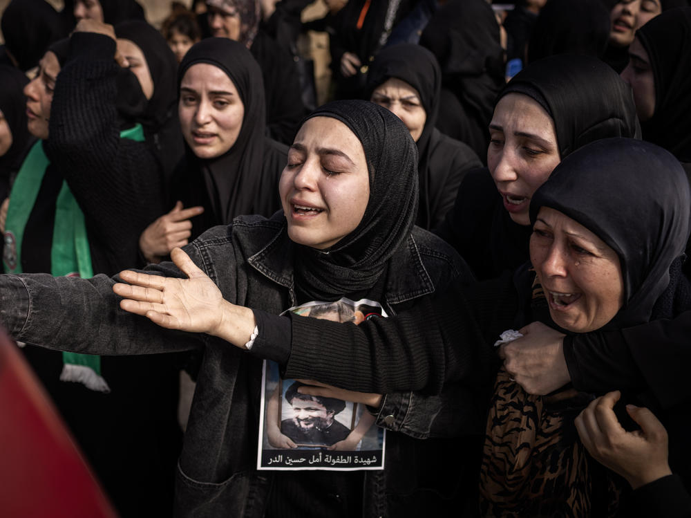 The family of Amal Hassan Al Durr, a 5-year-old girl, weeps inconsolably behind the ambulance transporting her body in Majdal Zoun, Lebanon, on Thursday, Feb. 22.