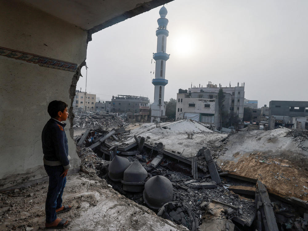 A child standing inside a damaged building stares at the Al-Faruq mosque, leveled by Israeli bombardment in Rafah on a foggy day on Sunday, Feb. 25.