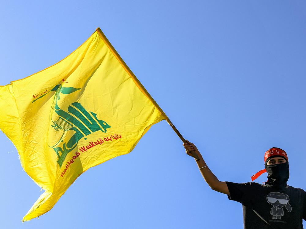 A masked demonstrator waves a flag of Hezbollah during a demonstration supporting the Palestinians in Beirut on Oct. 20, 2023.