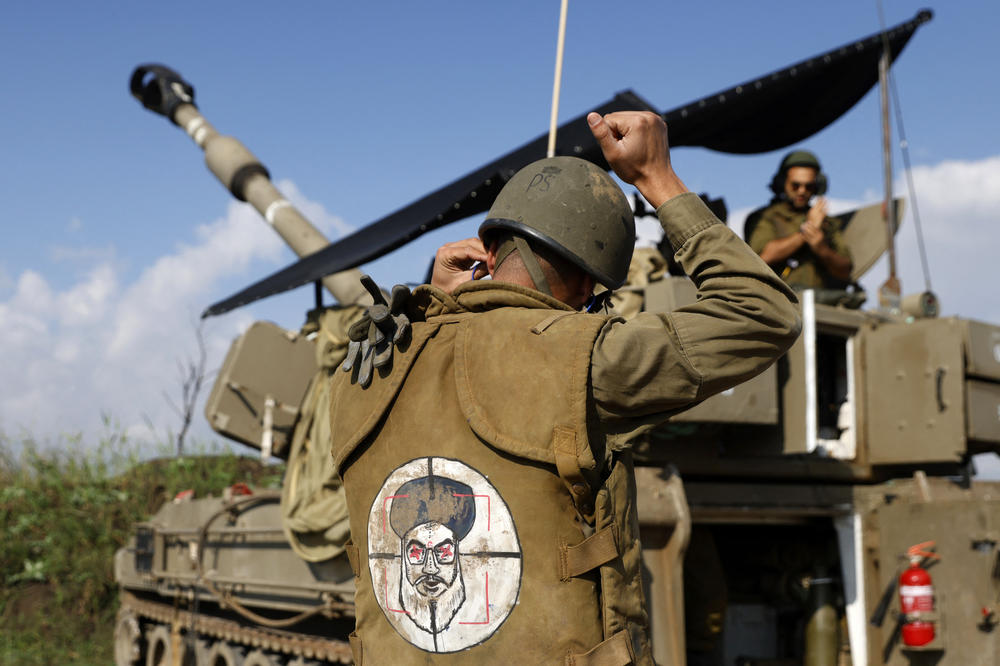 An Israeli soldier, wearing a patch on the back of his flack jacket showing Lebanon's Hezbollah leader Hassan Nasrallah as a target, stands in front of a self-propelled artillery howitzer in Upper Galilee in northern Israel, as an artillery unit shells southern Lebanon on January 4.