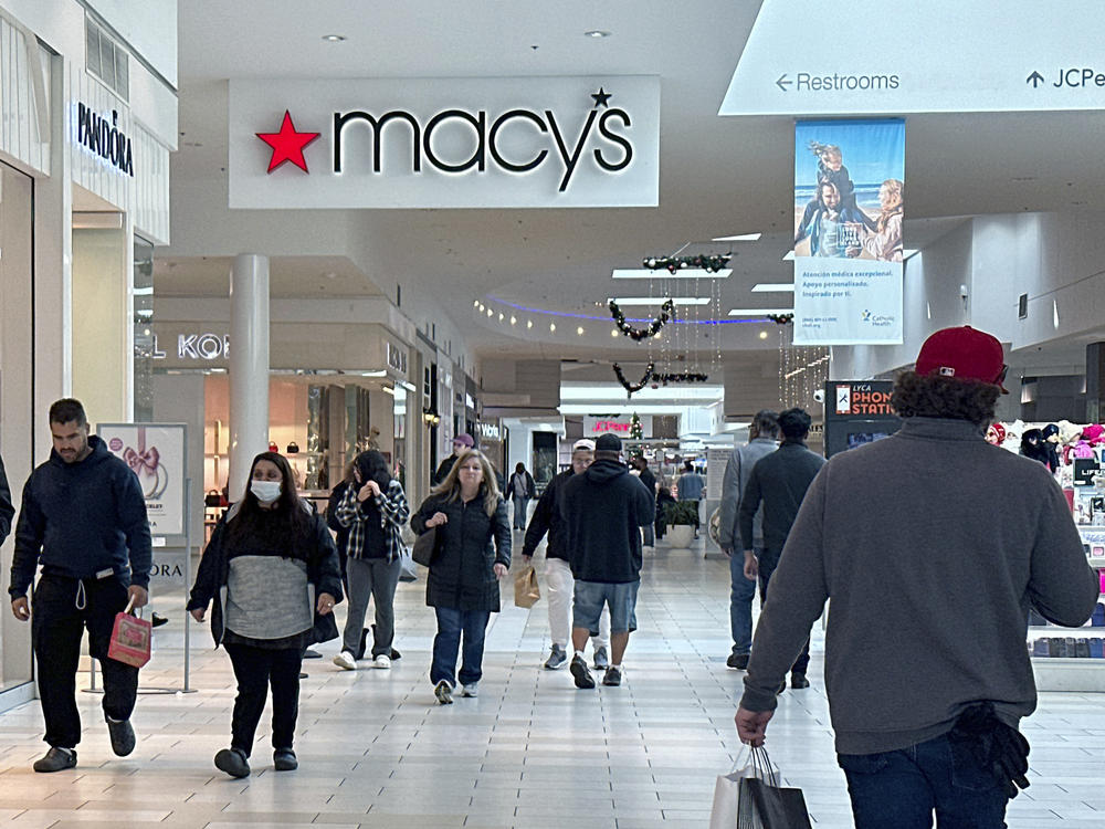 Shoppers walk by a sign for the Macy's department store at a mall in Long Island, N.Y.