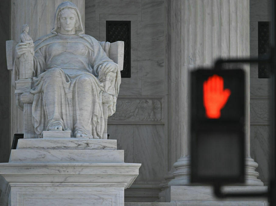 The Supreme Court, seen behind the stop light, is hearing arguments in a case testing the legality of a federal regulation banning devices that modify semiautomatic weapons to speed the firing mechanism.