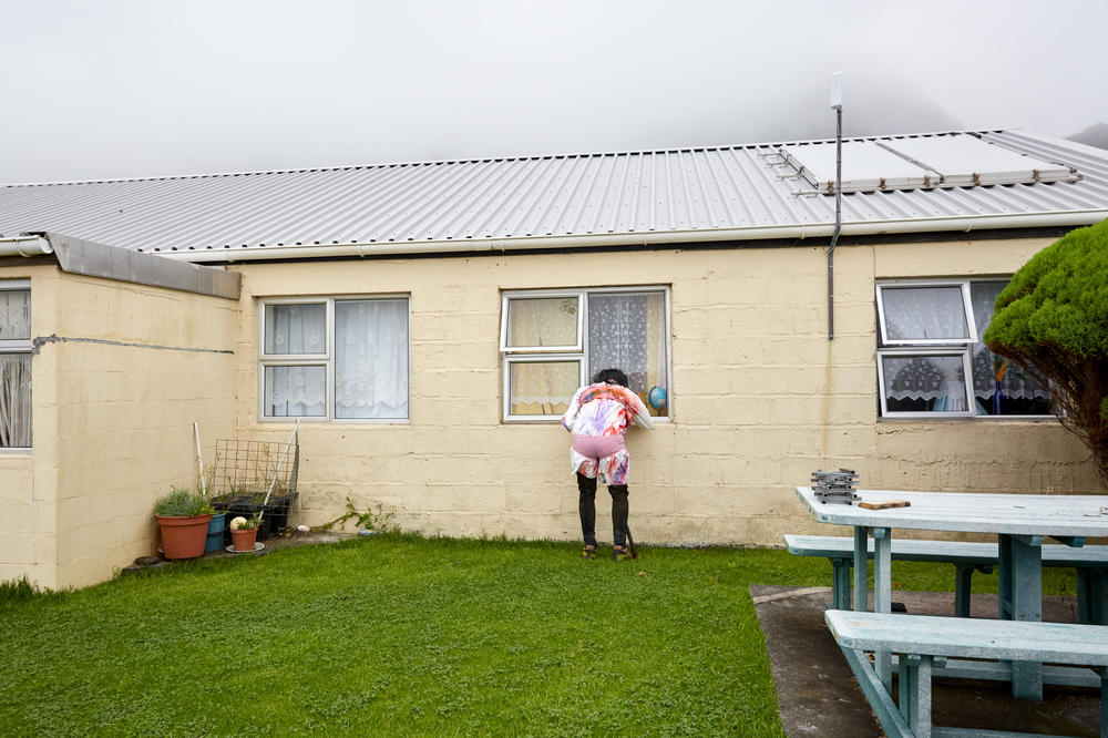 An Okalolie peers through the window of a house, looking for children to frighten. Tristanian women try to outsmart the Okalolies by hiding in groups behind locked doors. Where no 