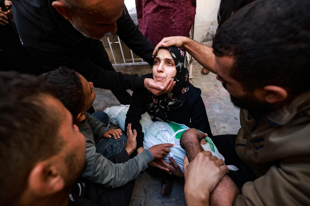 People try to comfort a woman holding the body of her baby girl killed in an Israeli strike in Rafah, southern Gaza Strip, in the courtyard of the al-Najjar hospital on Dec. 1, after battles resumed between Israel and Hamas.