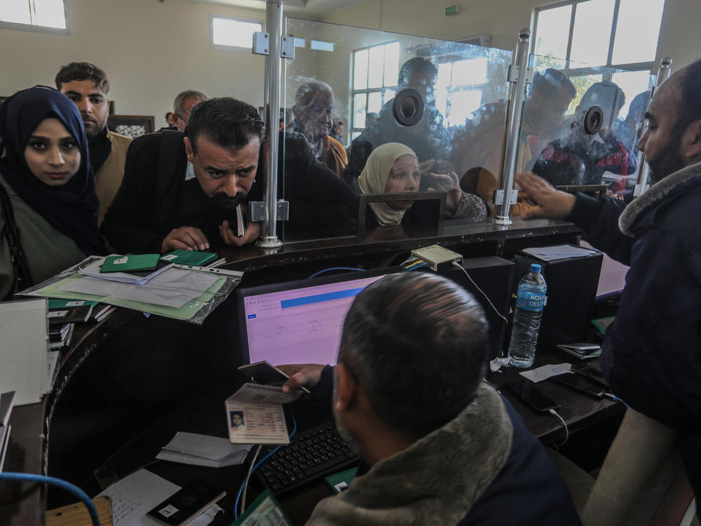 Palestinians who are foreign passport-holders get their documents checked to enter Egypt from the Gaza Strip through the Rafah border on Feb. 6. For most in Gaza — without foreign passports or approved reasons to leave such as for medical care — the only pathway out is to pay.