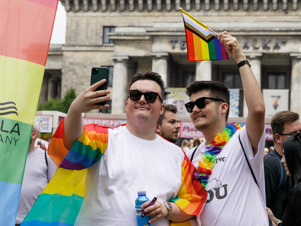 People take a selfie with rainbow Pride flags before the start of the Equality Parade in Warsaw, Poland, in June 2023. The Equality Parade was celebrated under the slogan 