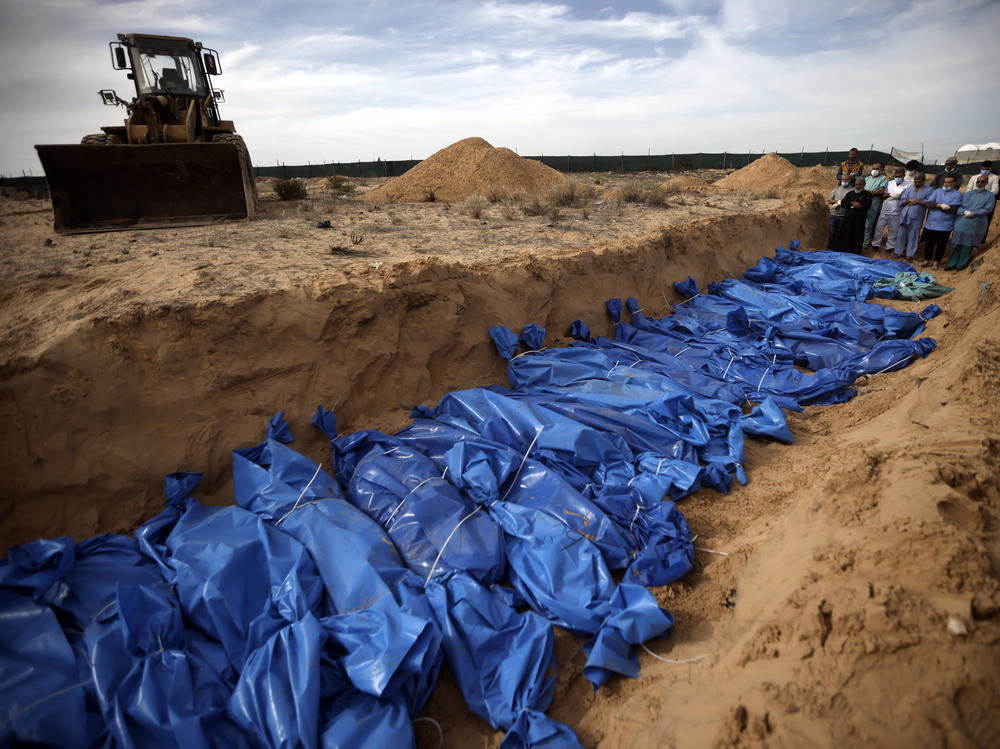 Palestinians pray over bodies of people killed in an Israeli bombardment, brought from the Shifa hospital, before burying them in a mass grave in the town of Khan Younis, southern Gaza Strip, Nov. 22.