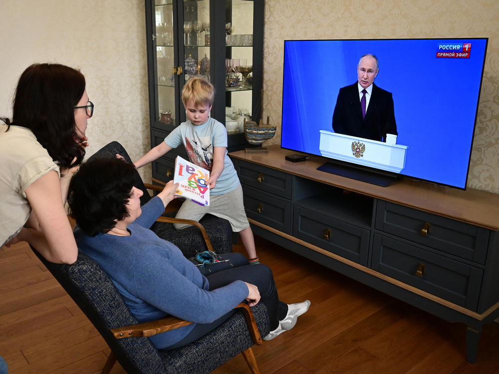 A family watches a TV broadcast of Russian President Vladimir Putin's annual state of the nation address in Moscow on Thursday.