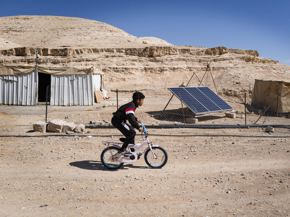 A boy rides a bicycle in a Bedouin camp receiving mobile health treatment. Mental health care providers say they worry about the toll that the war in Gaza, as well as settler violence, is having on West Bank residents — children in particular.