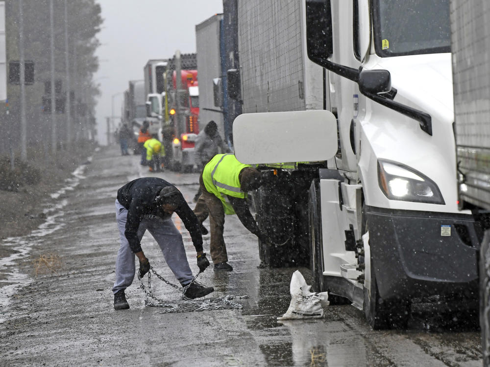 A long line of trucks are parked off the west bound I-80 as drivers put chains on the truck wheels in preparation for the snow storm over the Sierra Nevada on Thursday, Feb. 29, 2024, in Lake Tahoe, Calif.