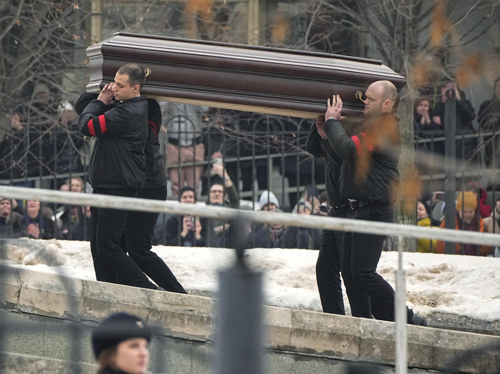 People watch as workers carry the coffin of Russian opposition leader Alexei Navalny to the Church of the Icon of the Mother of God 