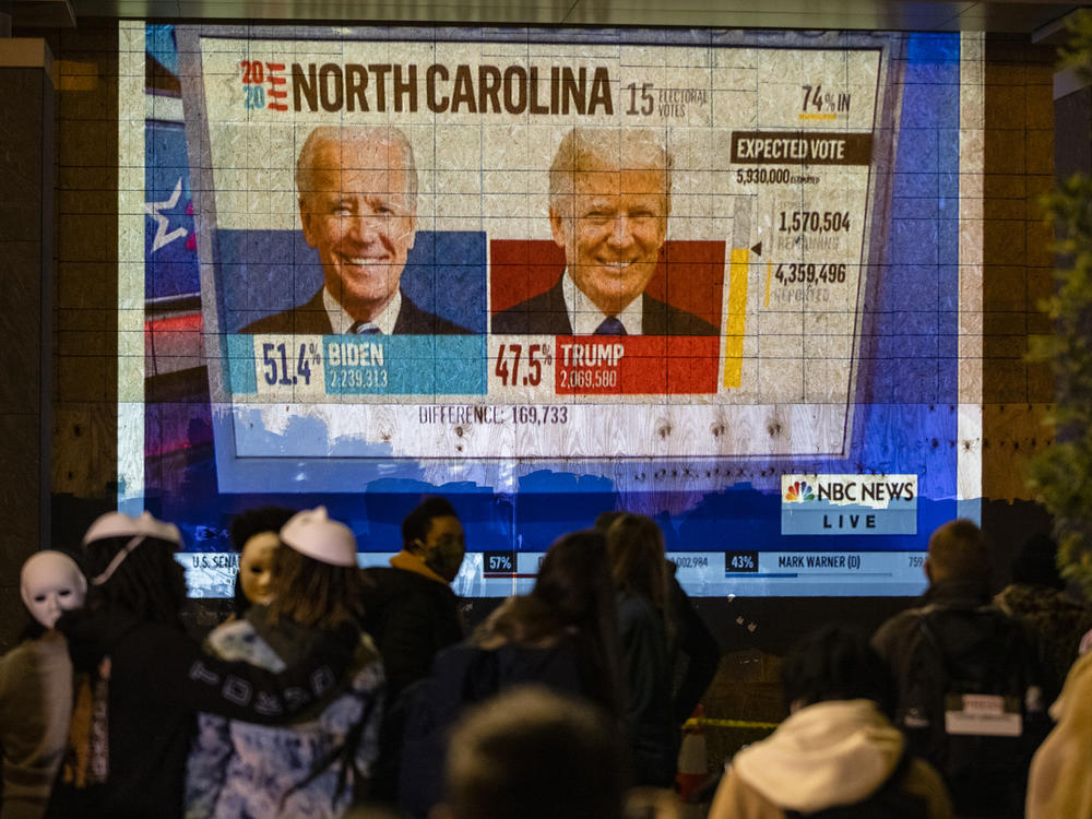 People watch a projection on the side of a building in Washington, DC as poll reports begin to roll in Election Day, November 3, 2020 in Washington, DC. After decisive primaries in Michigan and South Carolina, the 2024 race for President is shaping up to be a rematch.