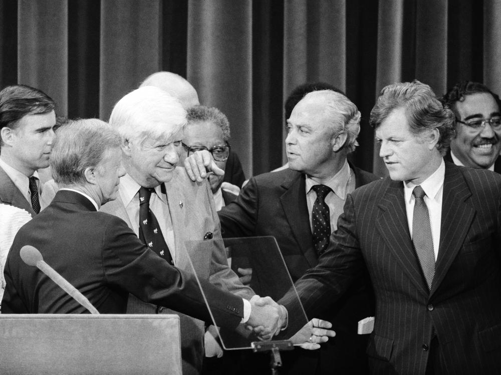President Carter and Sen. Edward Kennedy finally shake hands as Democratic Convention Chair Tip O'Neill and Carter campaign manager Robert Strauss bring them together on the podium at the conclusion of the Democratic Convention.